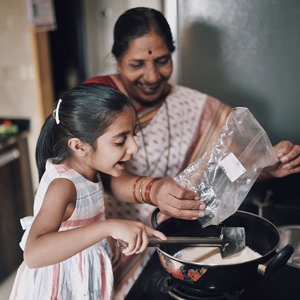 An Indian woman and small girl cook together in a kitchen