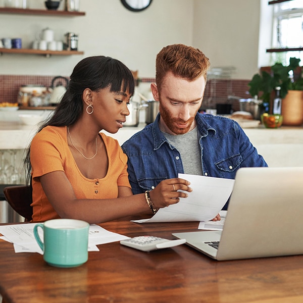 A young couple reviewing information on a laptop computer in their kitchen