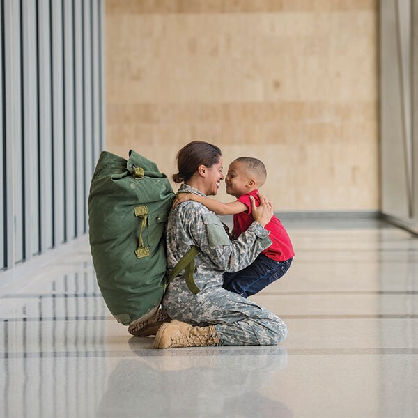 Military woman hugging young boy