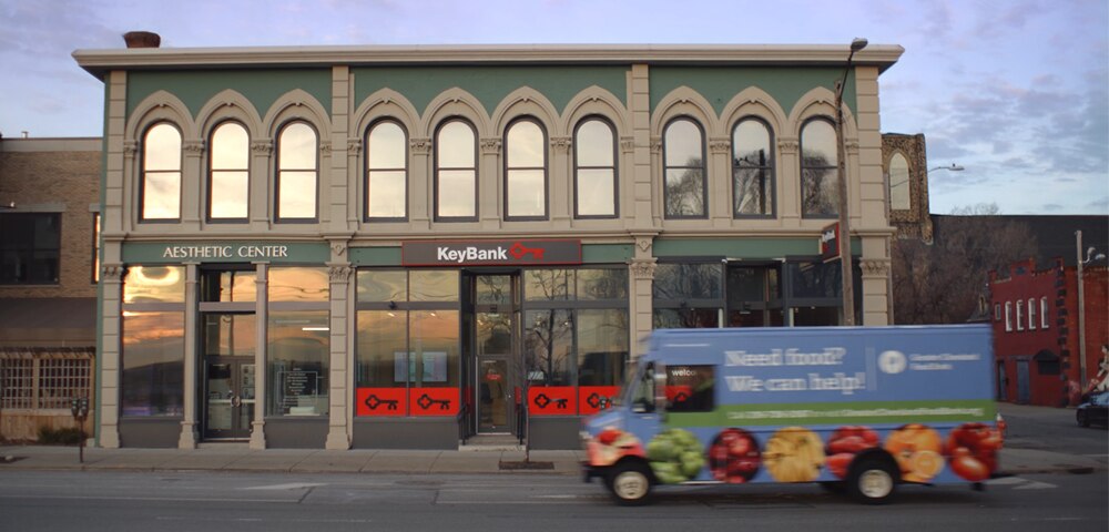 A truck from the Greater Cleveland Food Bank passing in front of a KeyBank storefront on a city street