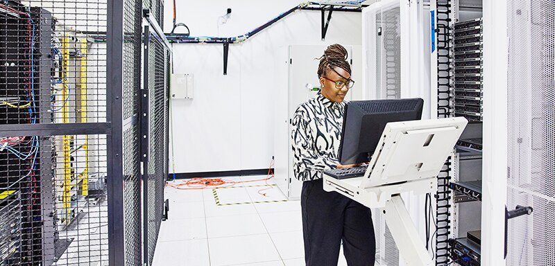 Medium wide shot of female IT professional configuring server in data center