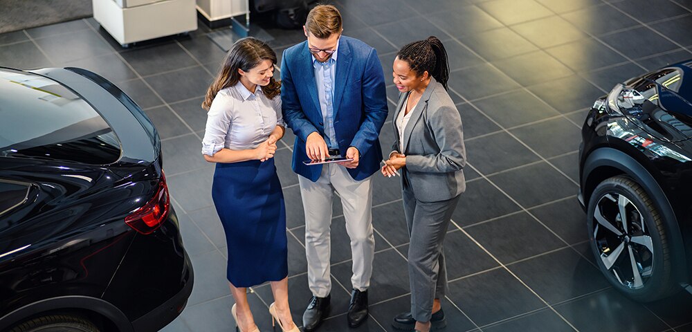 Above view of happy business people talking in a car showroom.