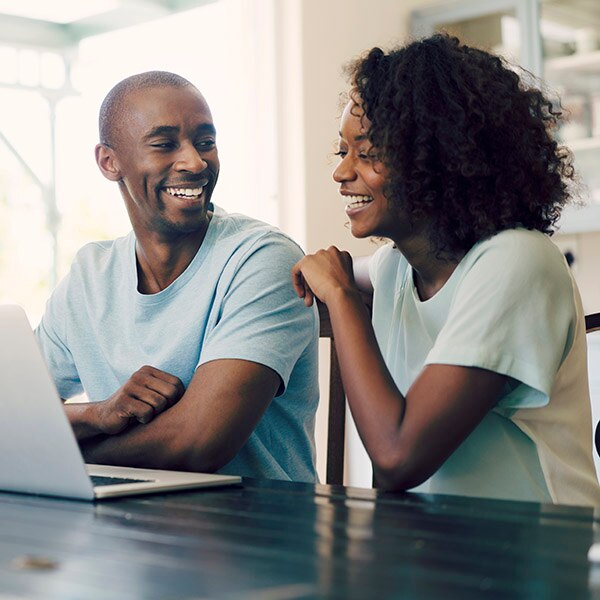 Laughing couple looking at laptop.