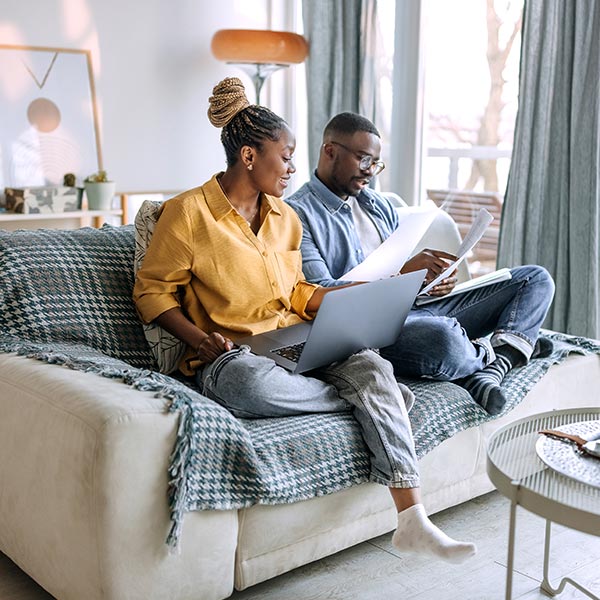 People sitting on couch with laptop and papers