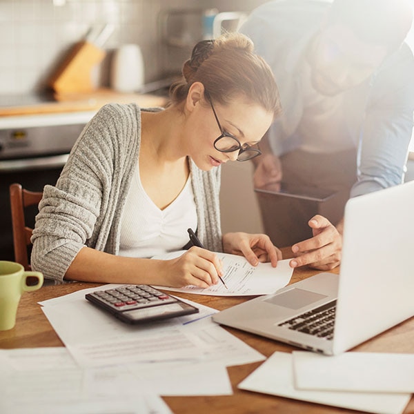 woman writing note with laptop open