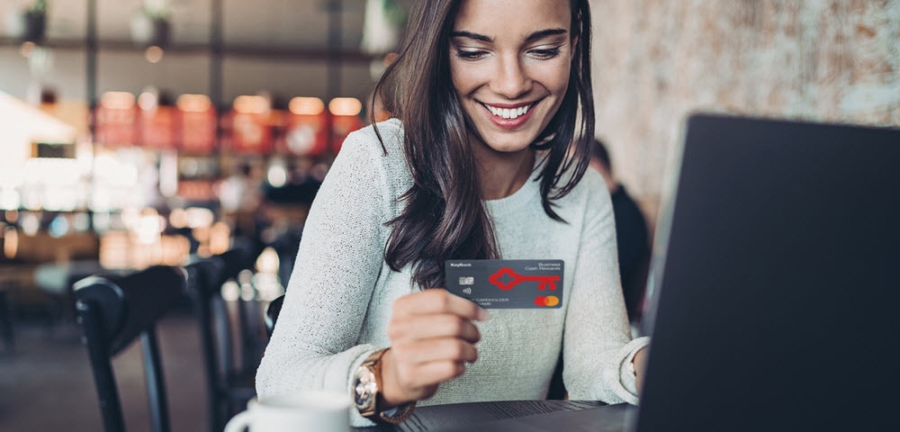 woman at table holding KeyBank Business Cash Rewards card