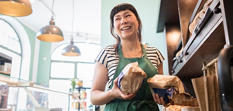 woman in bakery holding loaves of bread