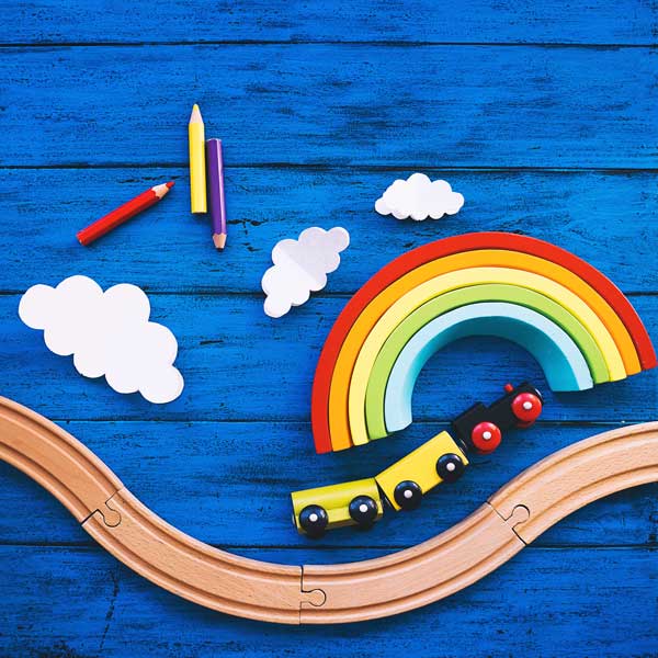 Child wood train with rainbow and clouds on a blue background