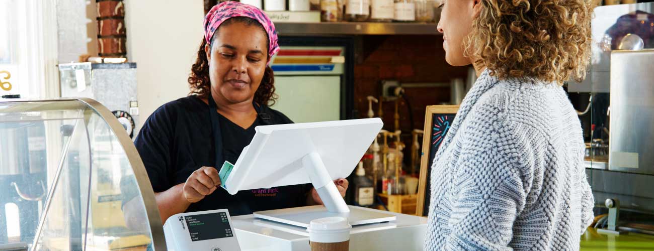 barista swiping customer credit card at coffee shop