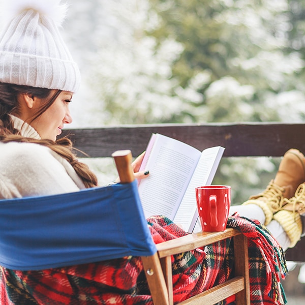 Woman reading outdoors bundled cozy up for winter weather